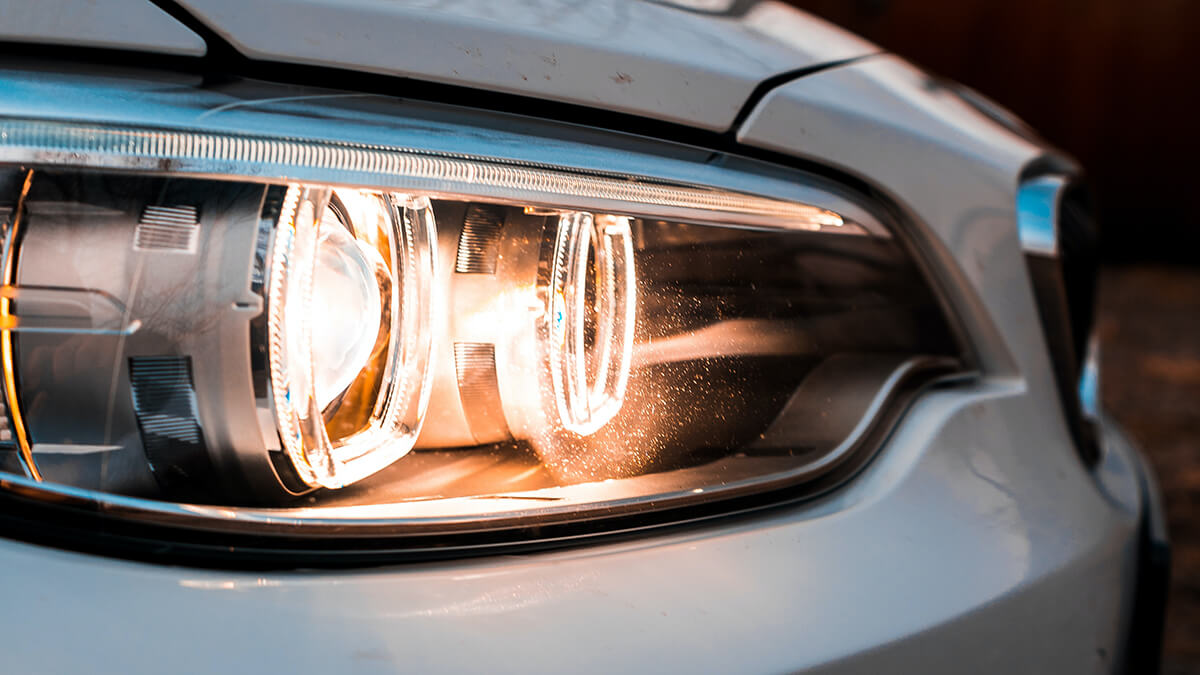 Yellow headlight bulb on the passenger side of a white car