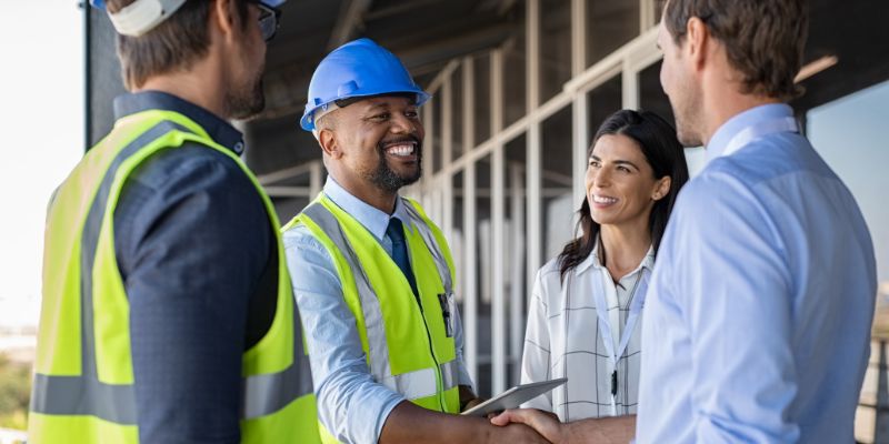 Construction worker smiling and shaking hands with clients